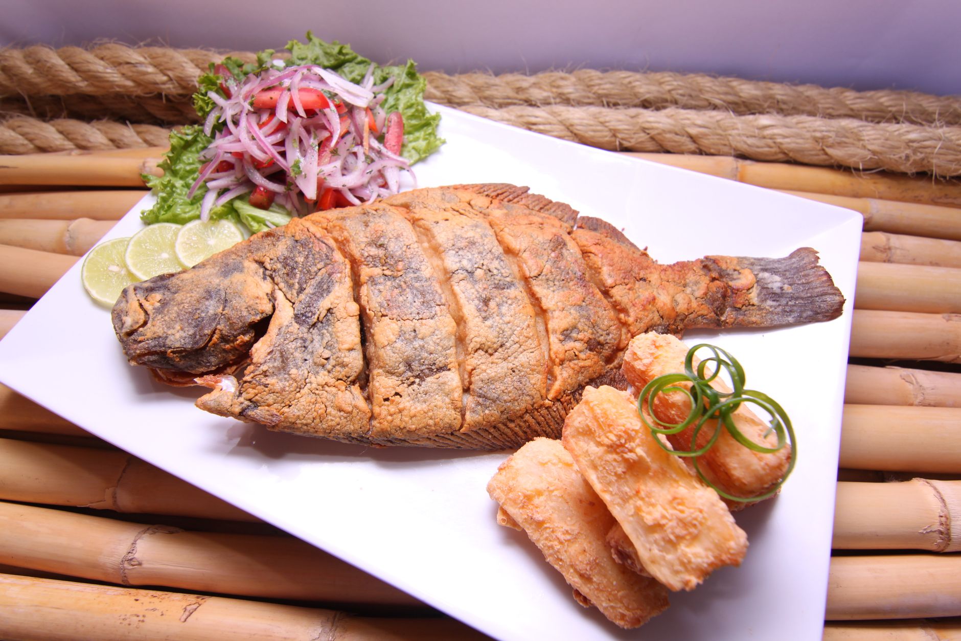 Crispy whole fried fish plated with lime and sides