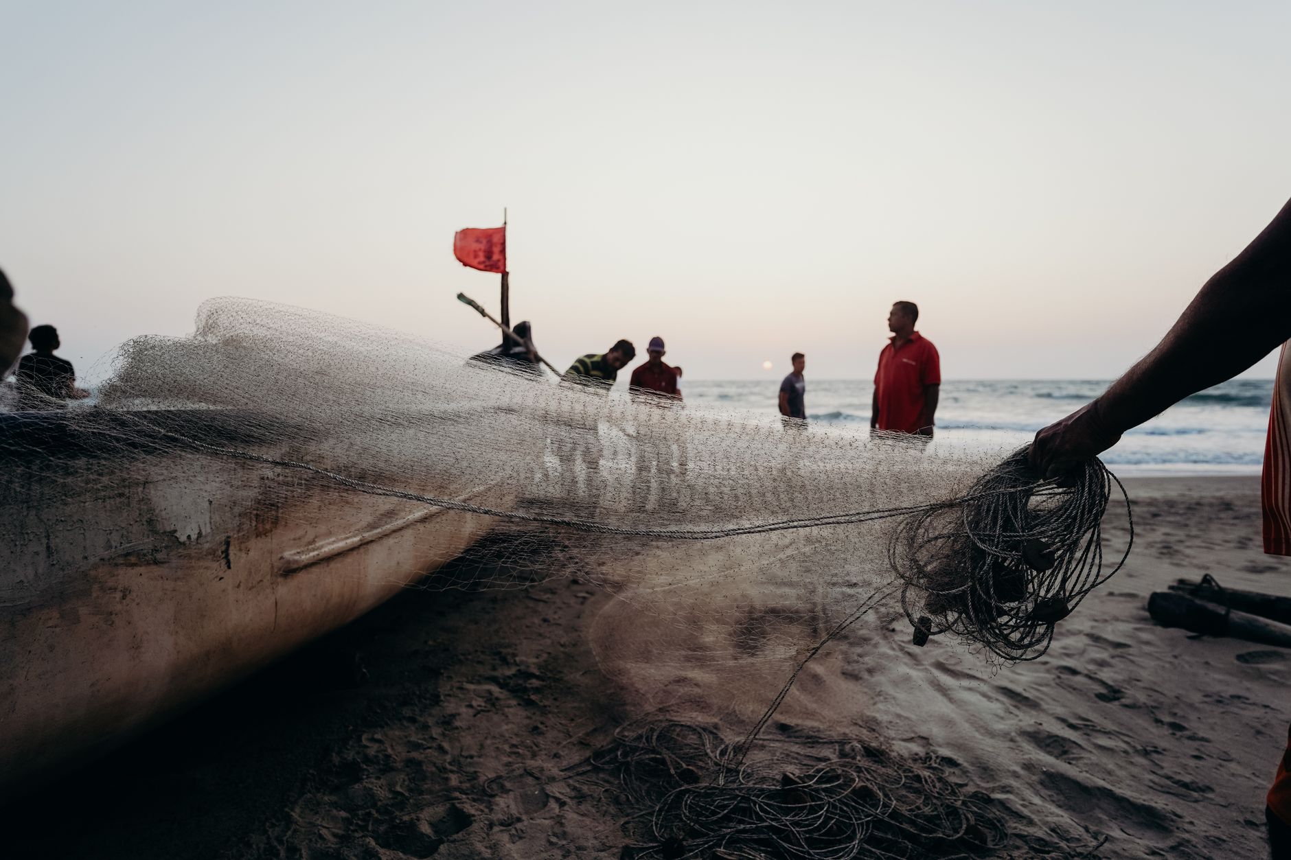 Fishermen preparing their nets on a beach in Goa at sunset